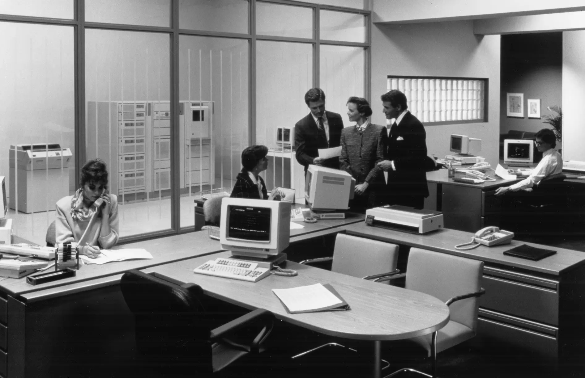 Oficina de finales de los 80 con empleados operando terminales IBM AS/400.